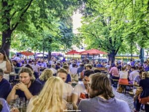 This image features a group of people enjoying an afternoon at a Beer Garden in Germany. 