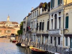 This image features a view of a Venice canal with a line of boats beside a row of homes.