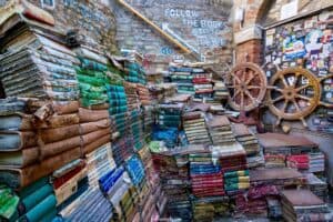 This image features Libreria Acqua Alta, a quirky famous bookstore in Venice, Italy. There are stacks and stacks of books surrounded by a brick wall.