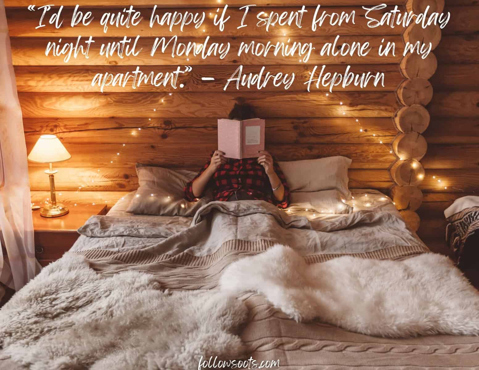 This image features a woman lying in her bed reading a book in front of her face. 