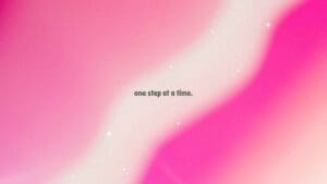 Pink Aesthetic Wallpaper with wavy backgorund of   differnet shades of pink. THe motivational quote in the middle says " One Step at a Time".
