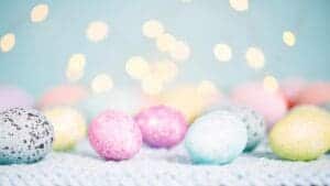 This images features pastel eggs of pink, blue and yellow colors with a soft bokeh background