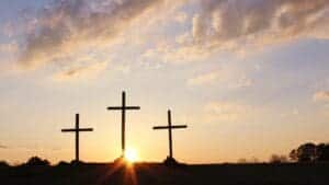 This image features three crosses with the sun rising up from behind them and a clouds high above