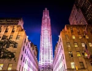 This image features a view looking up at  Rocefeller Center in NYC at night time. 
