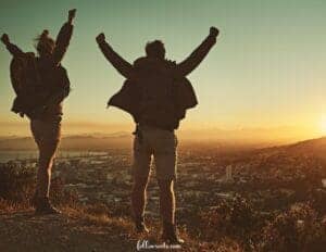 This image features tow people jumping up and down on a mountain to show their excitement to be traveling.