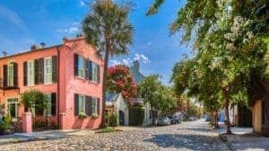 Chalmers Street cobblestone road in Charleston South Carolina’s French Quarter with historic homes, palm trees, and pastel buildings.
