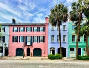 Pretty Places in Charleston - This image features an imageof Rainbow Row, which is an iconic section of colorful historic row houses that are blue, pink, purple and green