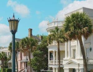 This image features a view of stately mansions in the background with a nantique lamp post in front of the left side.