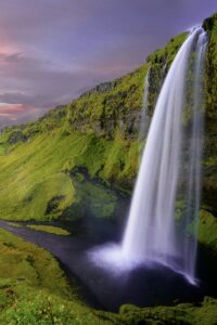 This image features a magnificent waterfall flowing off a high cliff in Norway