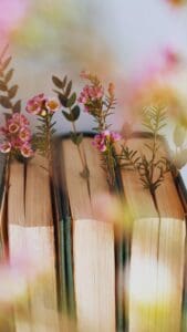 This image features three books on a shelf with petite flowerrs being used as bookmarks.