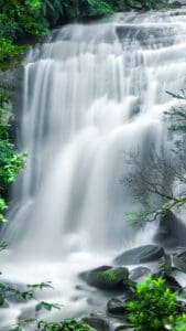 This image features a tall waterfall with water cascading down with a soft blur to the water. - Pretty Aesthetic Wallpapers