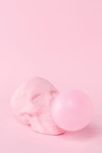 This image features a pink skull blowing a pink bubble from it’s mouth with a light pink background - Halloween Aesthetic Wallpapers