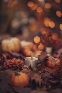 This image features a Cozy Autumn Scene with pumpkins, a candle and bokeh lights in the background. Halloween Backgrounds