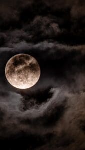 This image features a dark, cloudy and gloomy sky with a spooky full moon