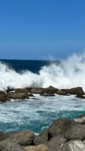 This image features waves crashing on black rocks with a pool of water in the foreground.