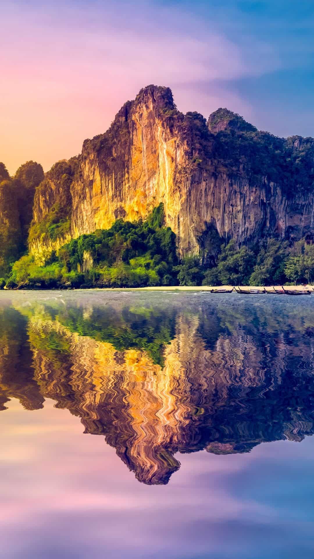 This image features a large golden mountain with water in front of it and a reflection of the mountain is in the water.