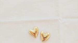 This image features two small golden mountain sitting hearts laying on a soft beige background