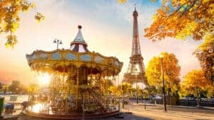 This image features the Eiffel Tower and the Merry Go Round in the park below it at sunset.