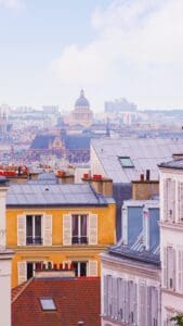 This image features colorful neighborhood rooftops with the Paris skyline in the distance