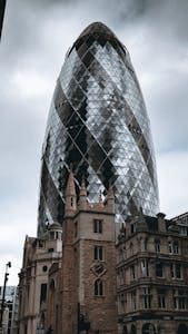 The Gherkin stands tall amidst historic buildings in London's urban landscape.
