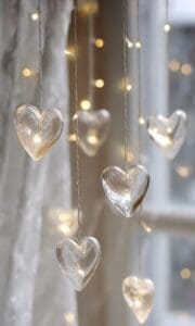 This Aesthetic Imagery wallpaper features hanging glass hearts in front of a window with gold string lights hanging with them