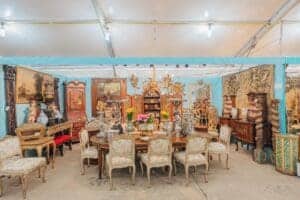 This image features a room full of vintage antique chairs and furniture 