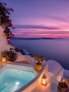 This image features a romantic evening by the pool overlooking a sunset in Mykonos.