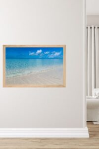 This image features a framed print of a sparkling blue ocean in Grand Cayman with soft white foaming ways coming on the sandy shore - Coastal wall art printable — Caribbean Blue