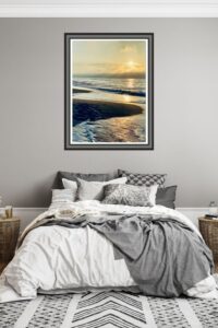 This image features a golden and glowing sunset in a frame over a cozy bed in colors of gray and white. - Golden Shore