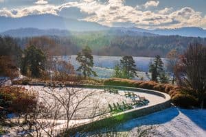 A scenic winter landscape featuring snow, mountains, and chairs under a blue sky. Asheville, NC is one of the Best US Winter vacations in the USA